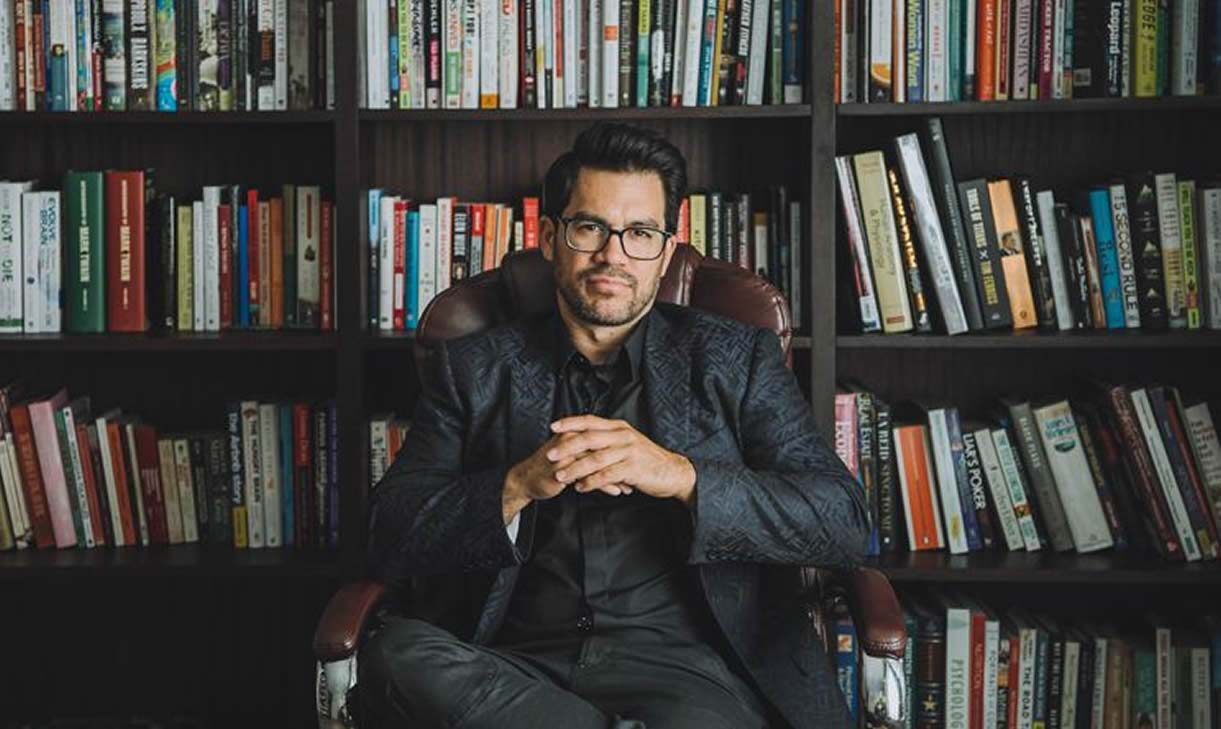 La photo représente Tai Lopez dans une bibliothèque